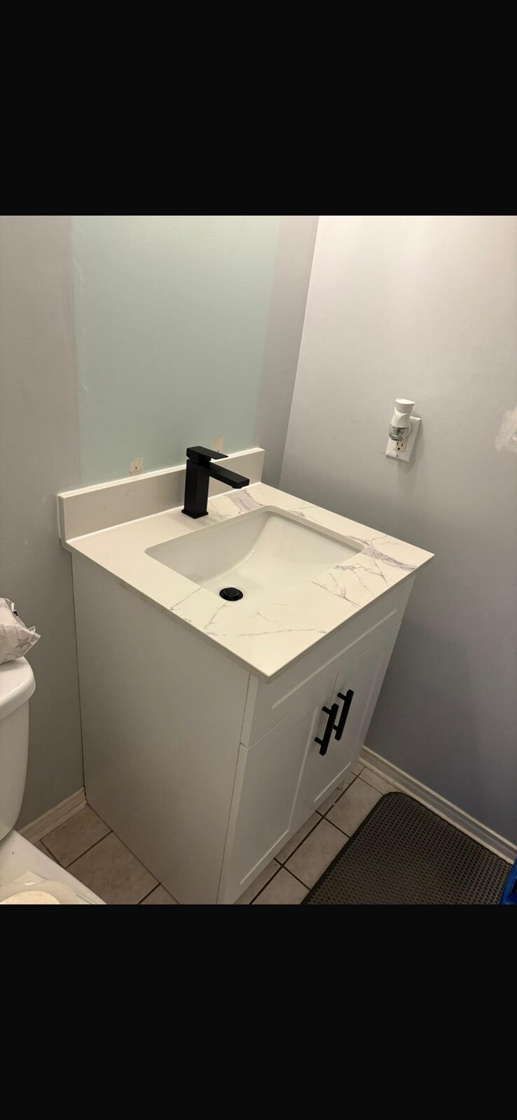 Finished bathroom vanity with matte black faucet and quartz top