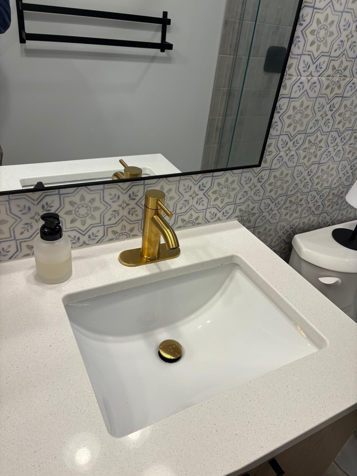 Ensuite vanity with brushed brass faucet and patterned tile